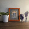 Waterfall Door watercolor painting displayed with amethyst crystals and houseplant