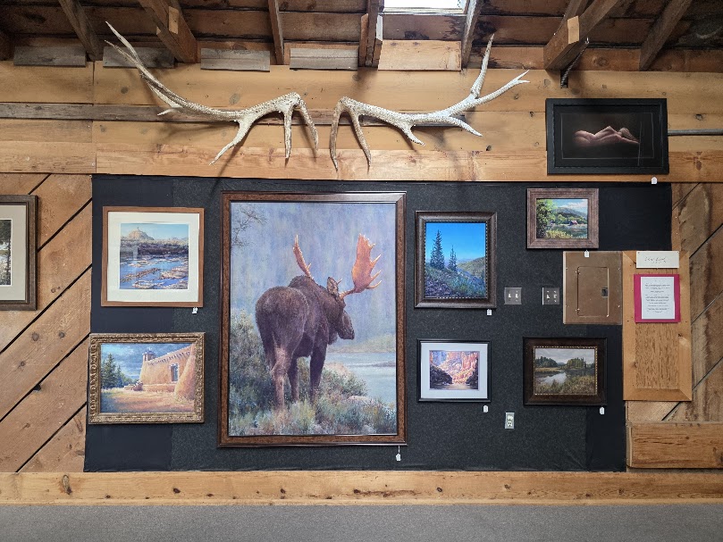 Wildlife and landscape paintings displayed in a traditional realism studio space.