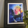 Framed Michael Bulloch signed print displayed on a wall beside a green houseplant