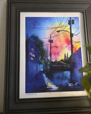 Framed Michael Bulloch signed print displayed on a wall beside a green houseplant