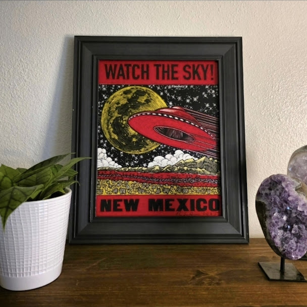 Red NM UFO Print Styled Framed Watch the Sky New Mexico UFO print displayed on a wooden shelf beside amethyst crystals