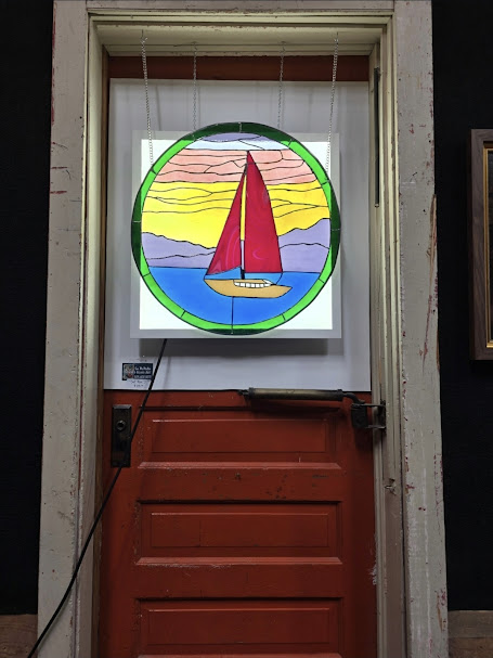 Stained glass sailboat artwork displayed inside Artifacts 302 coffeehouse and art studio.
