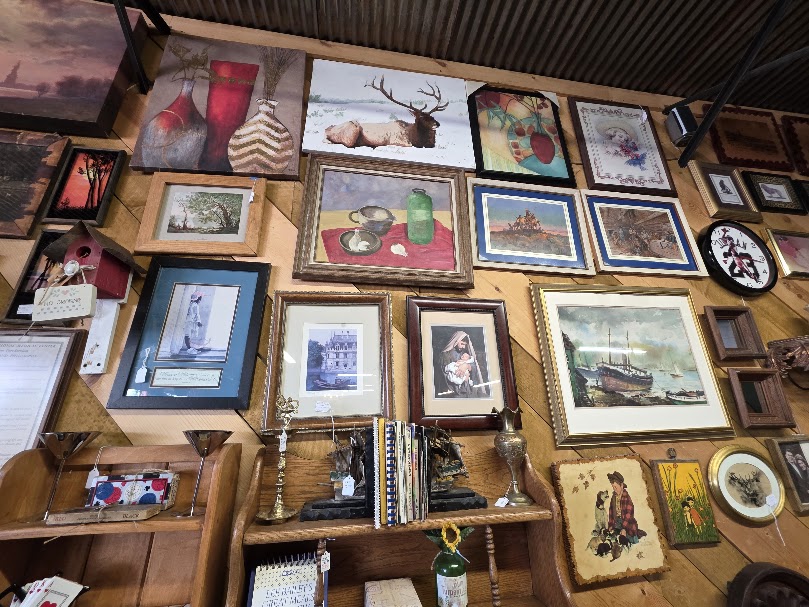 Decorative landscape paintings displayed at a thrift store.