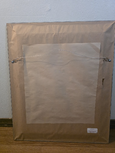 Back of a framed artwork showing paper backing and a storage pocket for artwork documentation.